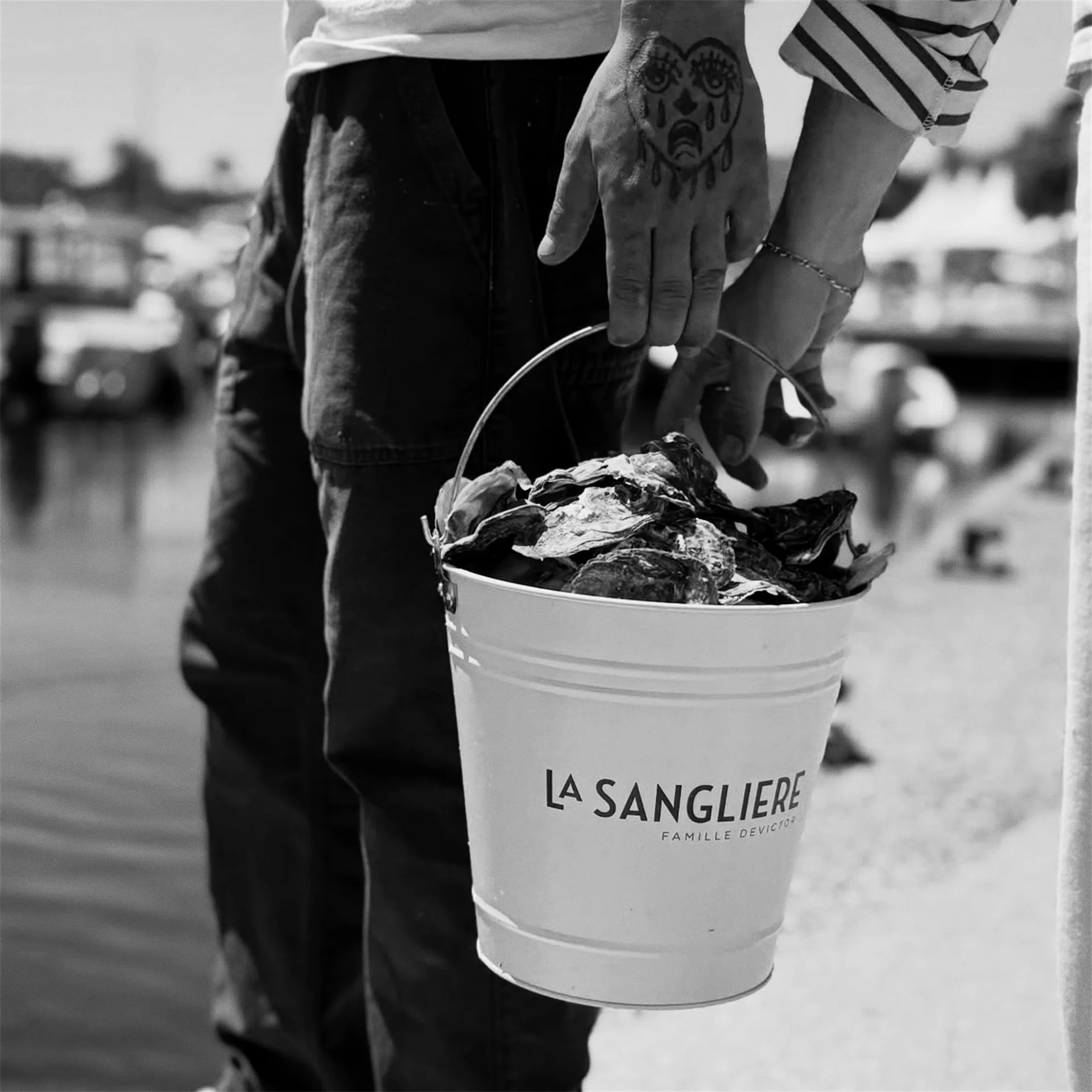 Seau La Sanglière rempli de coquilles d'huîtres au bord de l'eau